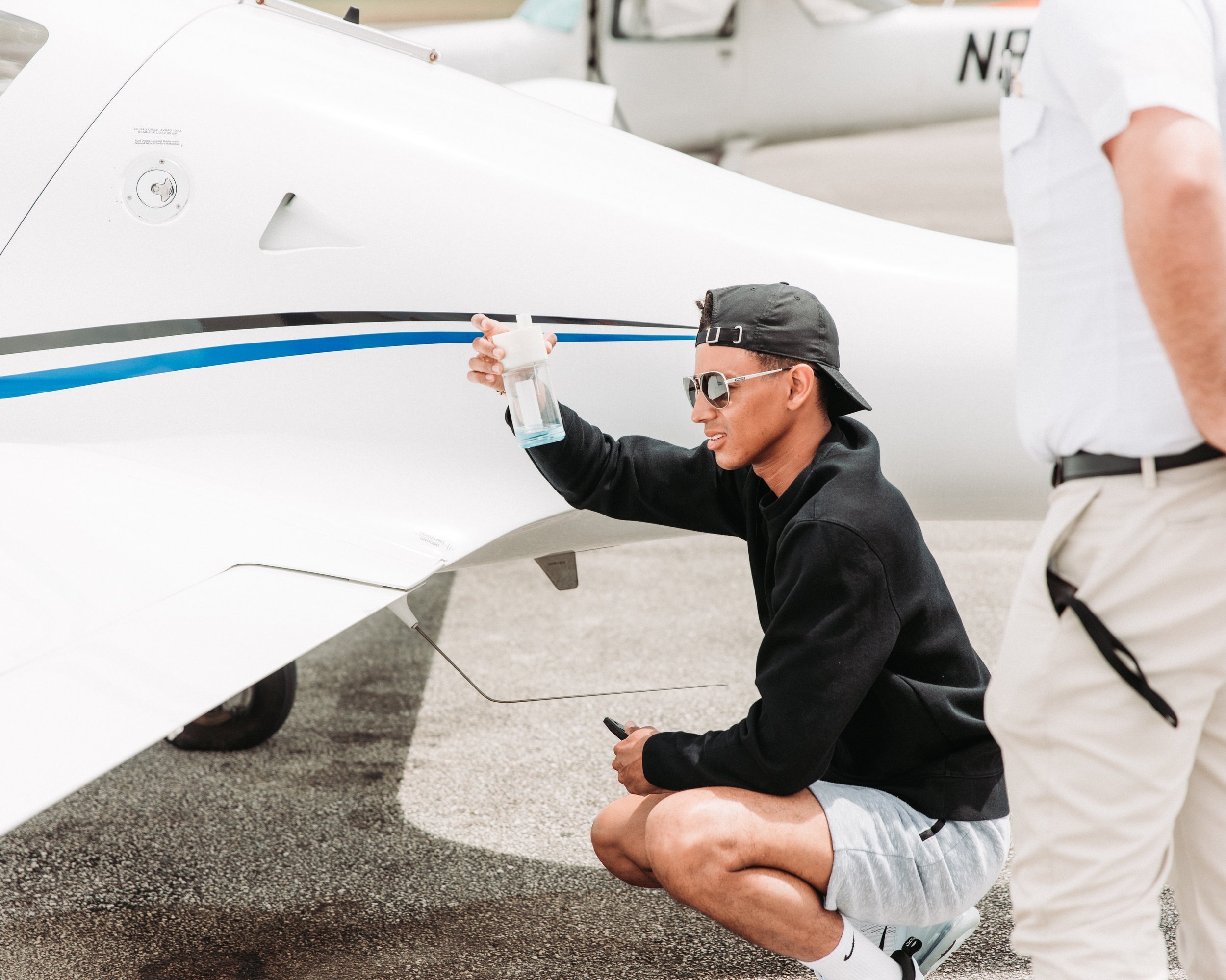 Student pilot checking fuel during pre-flight inspection.