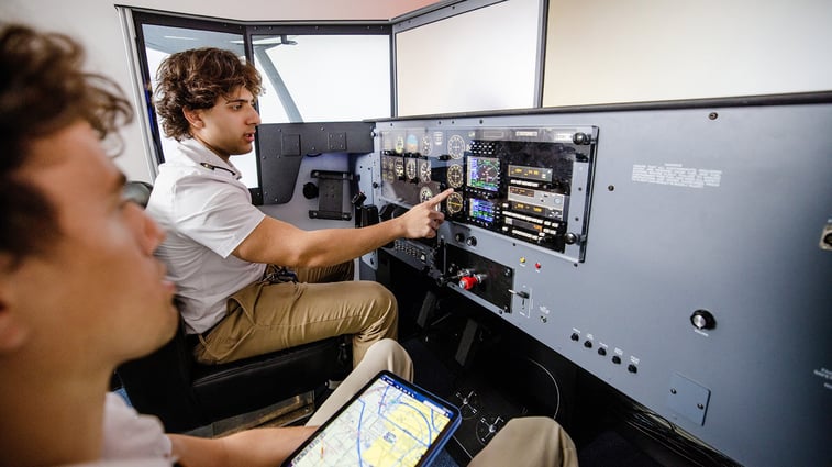 Student and flight instructor using a redbird flight simulator for training. 